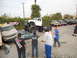 1986 Ford Bronco - A heavily modified white truck looms over damaged cars, with onlookers and other vehicles present at an outdoor event.