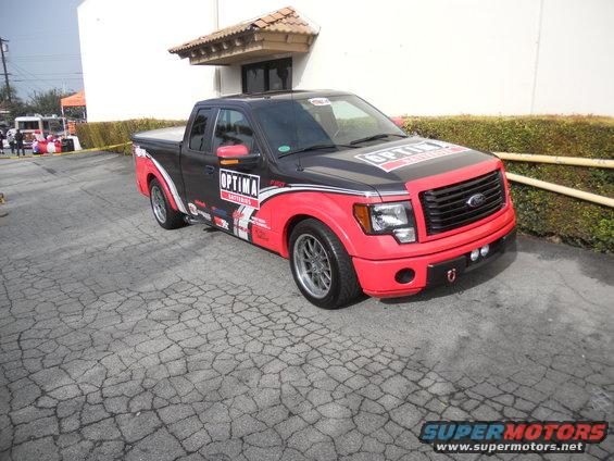 Black and red Ford F-150 pickup truck with Optima Batteries livery, 3/4 front view