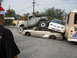 1986 Ford Bronco - A collection of damaged vehicles are stacked on a street, with a large truck crushing a sedan.