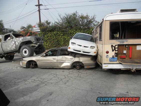 Wrecked cars and bus piled up, one car on top of another