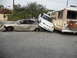 1986 Ford Bronco - Multiple vehicles are severely damaged and piled up on a street.