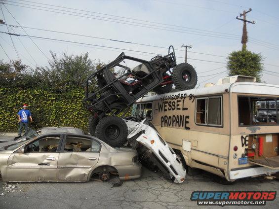 Scene of wrecked vehicles, including a bus with 'Wessel Propane' text, and a buggy on top