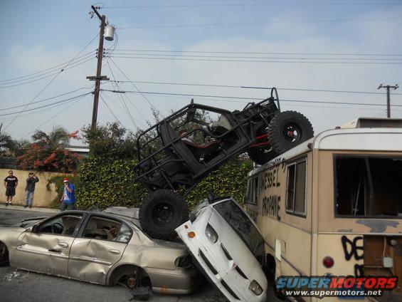 Off-road vehicle atop a bus, crushing cars below