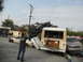 1986 Ford Bronco - A person captures a scene of destruction where several vehicles, including a bus and a buggy, are stacked and damaged on a street.