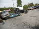 1986 Ford Bronco - A monster truck looms over two crushed cars, with a line of other trucks parked in the background.