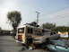 1986 Ford Bronco - Modified RV and stacked cars in a junkyard setting with graffiti and a banner.
