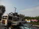 1986 Ford Bronco - A collection of vehicles, including a bus and several cars, are piled up in an outdoor lot.