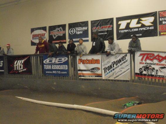 Remote control race track with spectators watching, banners for racing brands overhead