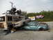 1986 Ford Bronco - Multiple wrecked vehicles and a bus are piled up, with a buggy on the bus's roof.