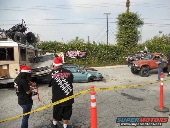 Damaged cars and a bus with a buggy on top, cordoned off with yellow tape