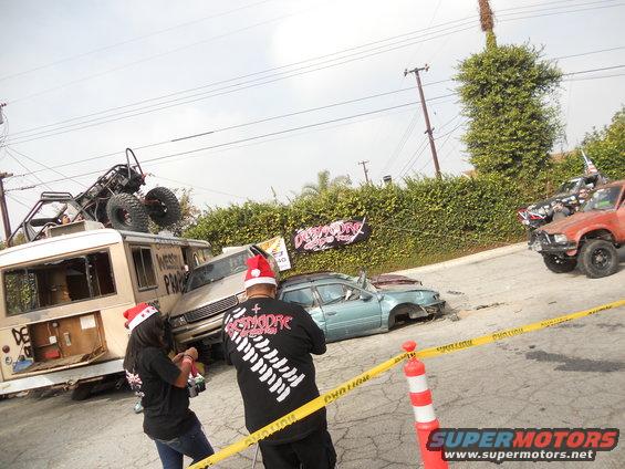 Scene of a car crush event with damaged vehicles and people in Santa hats