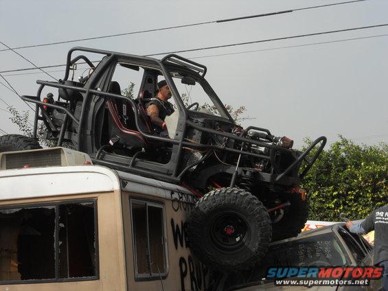 Off-road buggy on top of a bus, driver visible