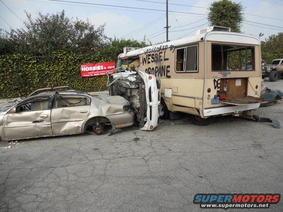 Gold sedan and a white car are crushed against the side of a bus that says 'WESSEL PROPANE'