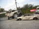 1986 Ford Bronco - A lifted monster truck is shown crushing a gold sedan, with a sign for 'Hobbies & Toys' visible in the background.