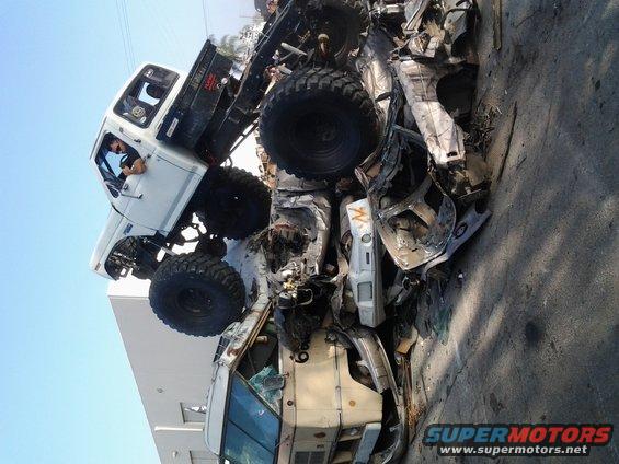 Two heavily damaged vehicles piled up, one a white truck with large tires