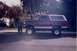 1992 Ford Bronco - A man stands next to a lifted maroon 1992 Ford Bronco with a white top.