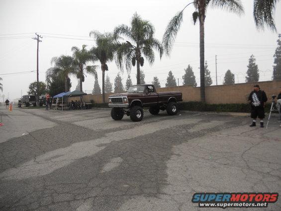 Maroon lifted pickup truck with large tires, seen from a 3/4 front angle