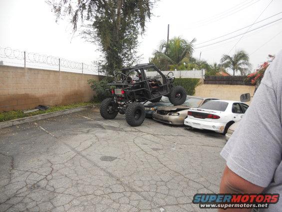 Buggy on top of two wrecked cars in a parking lot