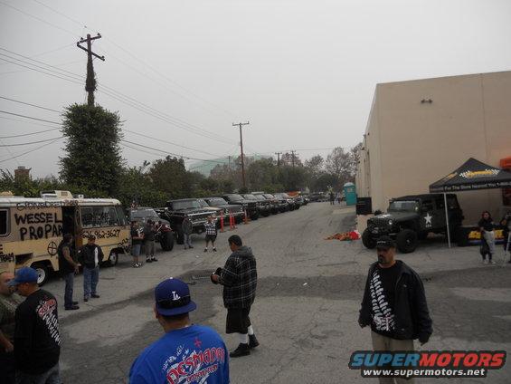 Line of trucks and SUVs parked on a street with a van and a military-style Jeep