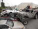 1986 Ford Bronco - Several heavily modified trucks are stacked on top of passenger cars in a lot.