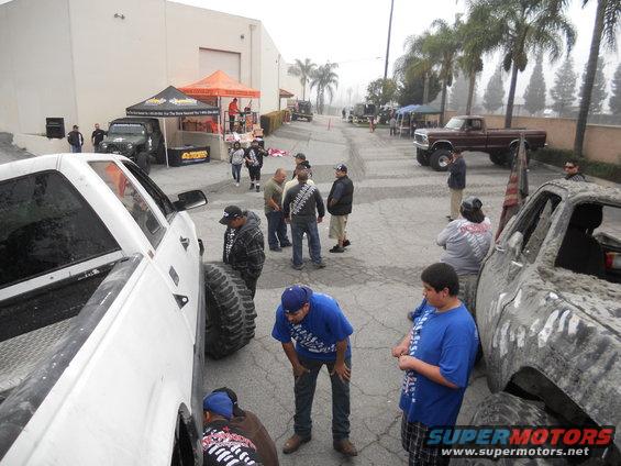 Side view of a lifted pickup truck with oversized tires, people inspecting it
