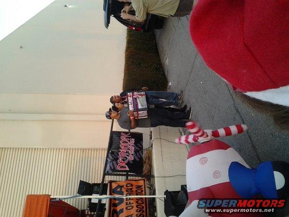 People stand near a building and an inflatable decoration. Signs are visible