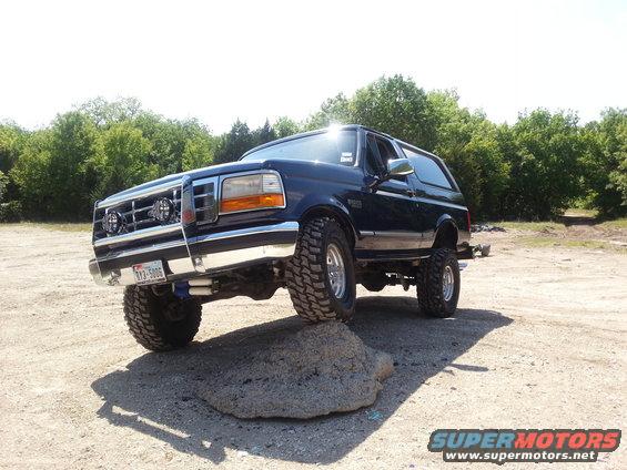 Dark blue Ford Bronco on a rock, front right tire elevated