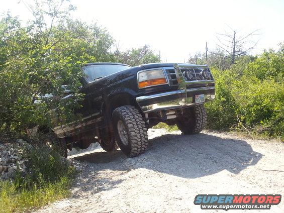 Black 1995 Ford Bronco with lifted suspension and off-road tires navigating a dirt trail
