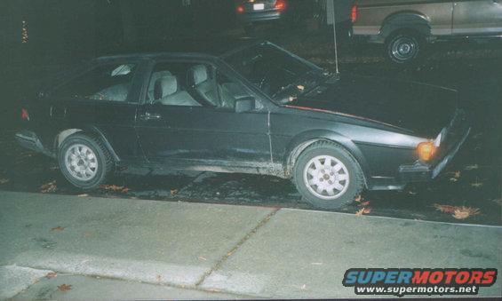 Black 1985 Volkswagen Scirocco parked on street at night, other vehicles visible in background