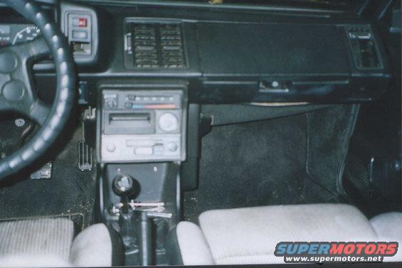 Interior view of a 1985 Volkswagen Scirocco showing the dashboard, steering wheel, gear shifter, and passenger seat