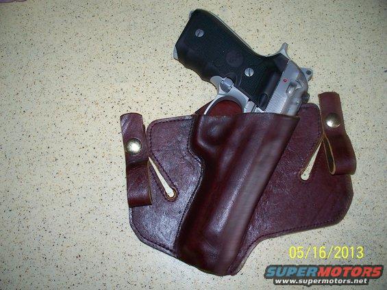 Pistol in a brown leather holster on a speckled surface. Date stamp 05/16/2013 and SuperMotors.net logo visible