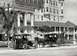 1909 Ford Model T - A 1909 Ford Model T is parked beside a horse-drawn carriage in front of a large building.