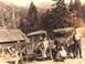 1909 Ford Model T - Two trucks and a group of people pose for a photo in a mountainous, wooded area.