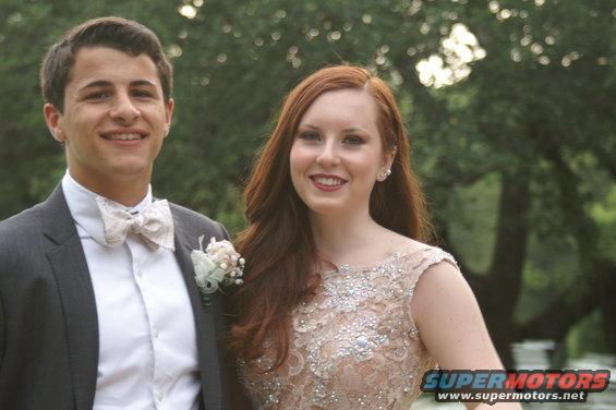 Guy in suit and bow tie with girl in sparkly dress, outdoors