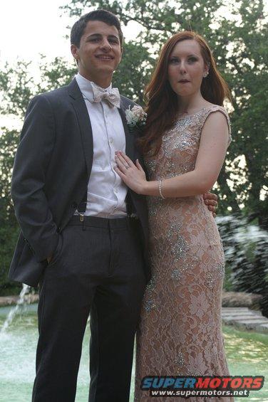 Couple posing for a photo at prom with a fountain in the background