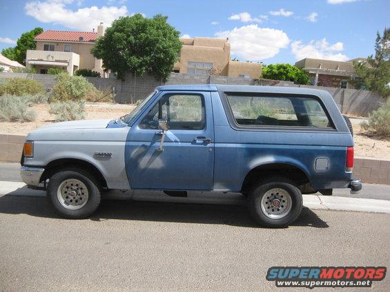Side view of a blue and silver Ford Bronco parked on a street