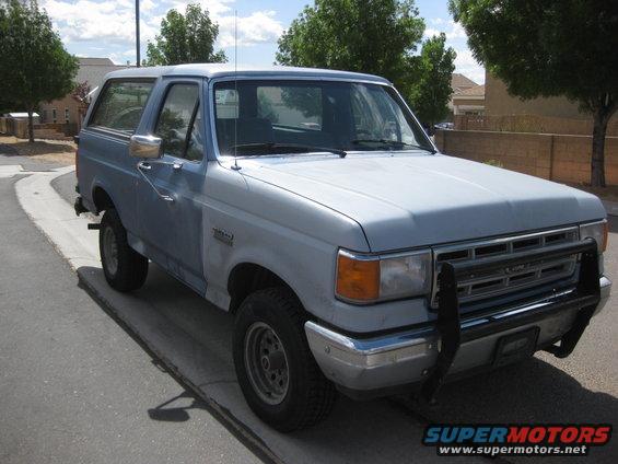 Light blue 1987 Ford Bronco with a black bull bar parked on a street