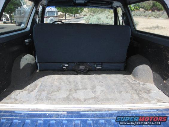 Interior cargo area of a blue SUV, showing the rear seat and wheel wells