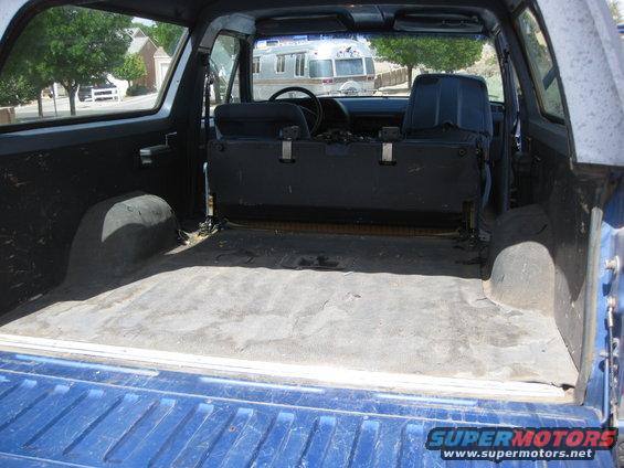 Back cargo area and rear seats of a blue SUV. An Airstream trailer is visible through the rear window