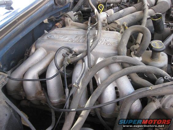 Ford engine intake manifold with "Electronic Fuel Injection" text. Hoses and wiring are visible