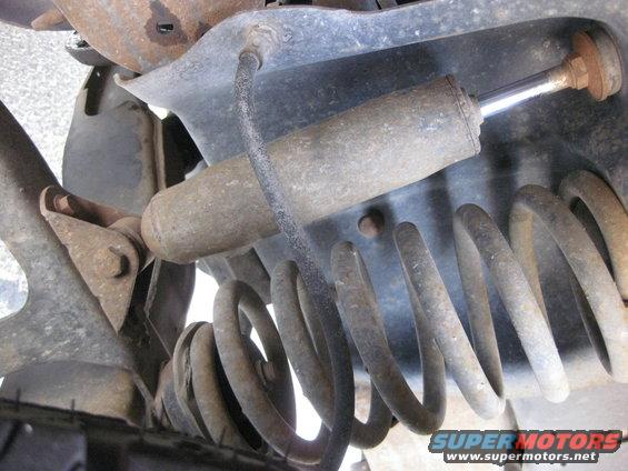 close-up of a rusty shock absorber and coil spring on a vehicle's suspension