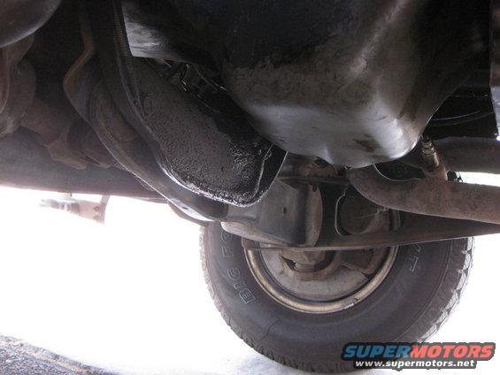 Underside view of a 1988 Ford Bronco showing the oil pan, exhaust pipe, and tire