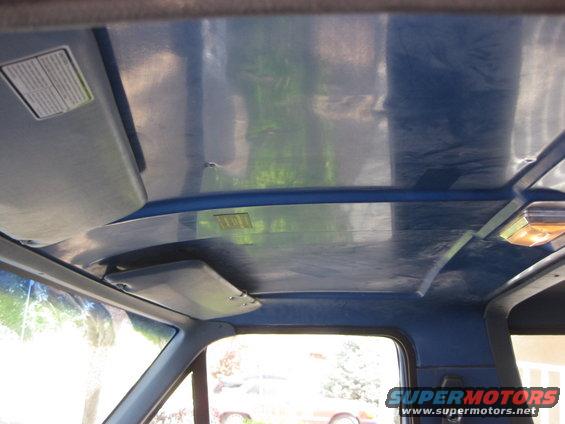 Interior shot of a vehicle's blue headliner with sun visors and a dome light