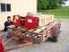 1995 Mercury Grand Marquis - A trailer carries red lifting equipment and boxed items, with a man securing the load. Text on the boxes indicates "HEAVY END" and "ROTARY…