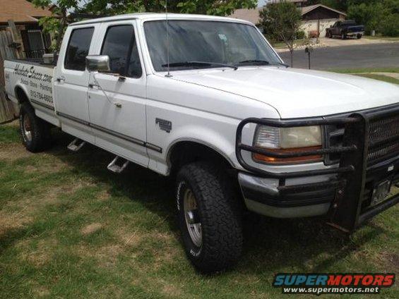 White crew cab pickup truck with a brush guard and running boards. Text on the door reads 'Allied Stone.com'