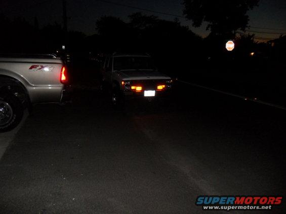 White 1994 Jeep Cherokee with hazard lights on at night