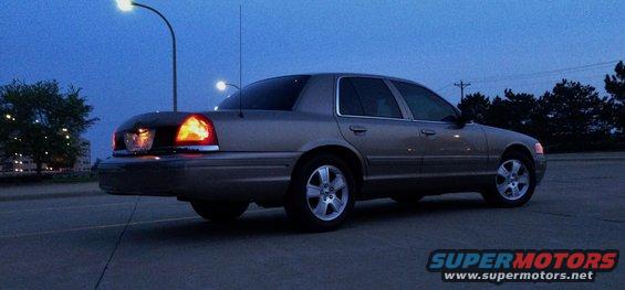 Tan 2003 Ford Crown Victoria, rear quarter view, parked on asphalt at dusk