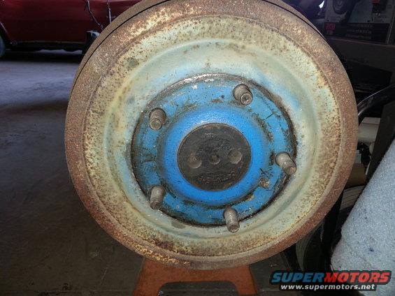 Close-up of a rusty vehicle brake drum with a blue hub