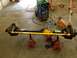 1988 Ford Bronco - Front axle assembly with yellow tie rod, supported by red jack stands, with a welding machine in the background.