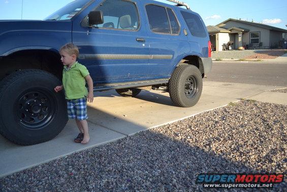 Blue 2004 Nissan Xterra with a child standing next to the front tire